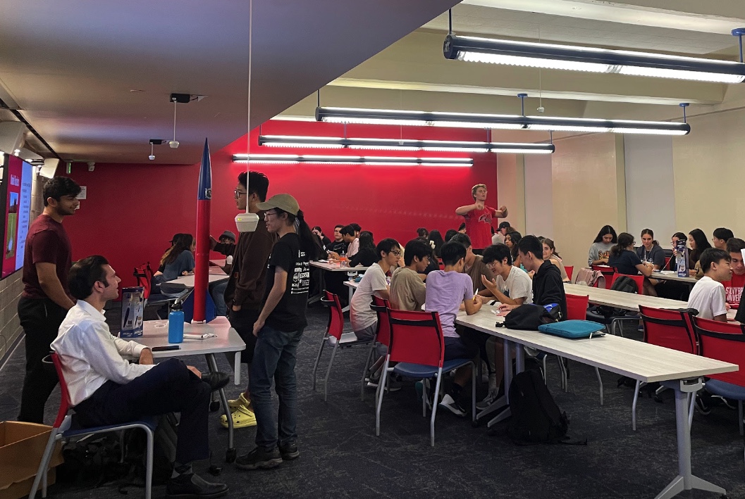 Student event with people sitting down and engaging at various tables.