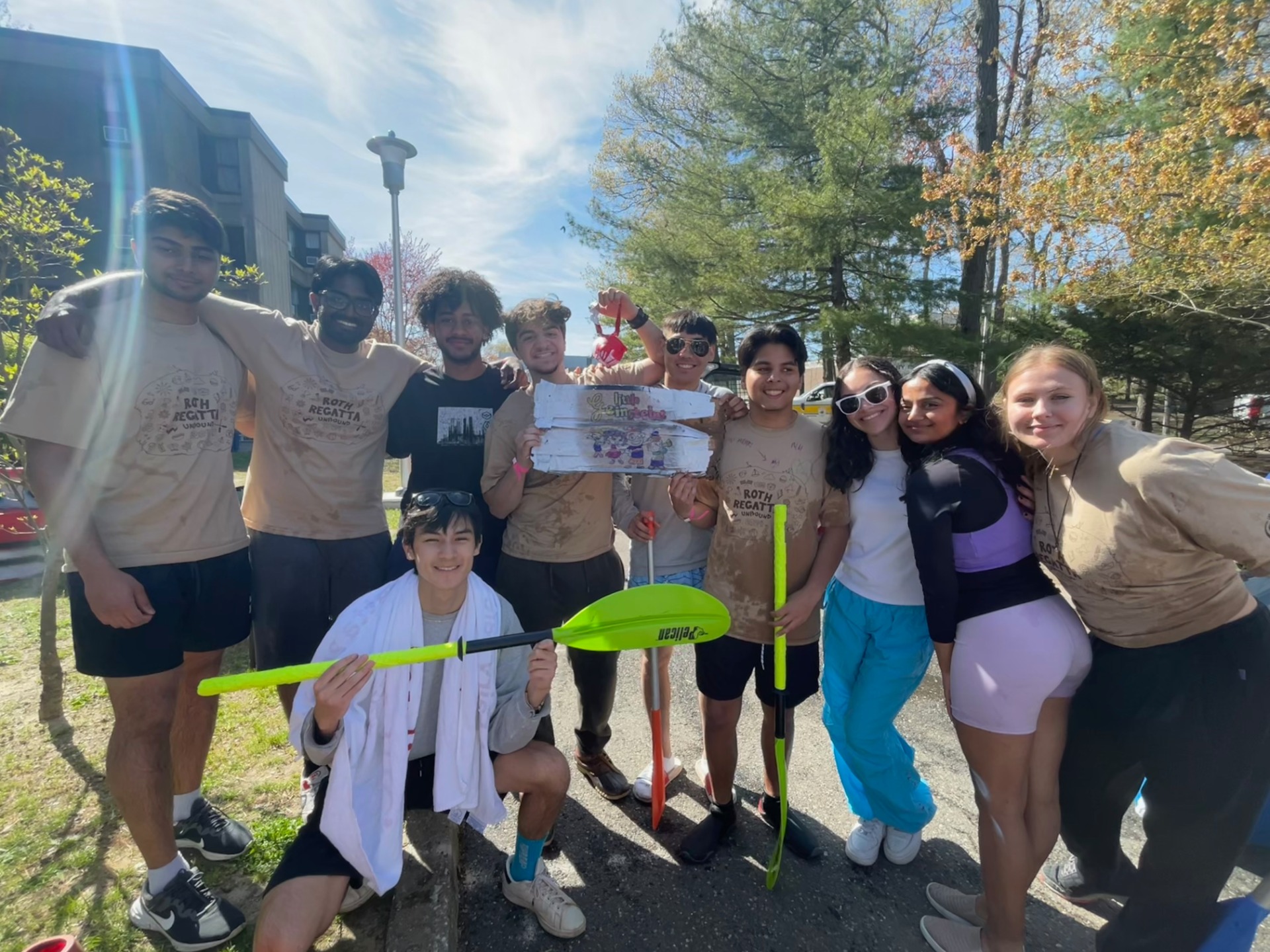 Students outside smiling and holding oars.