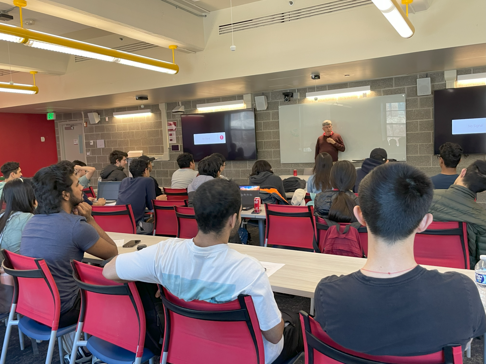 Students listening to professor at a club event.