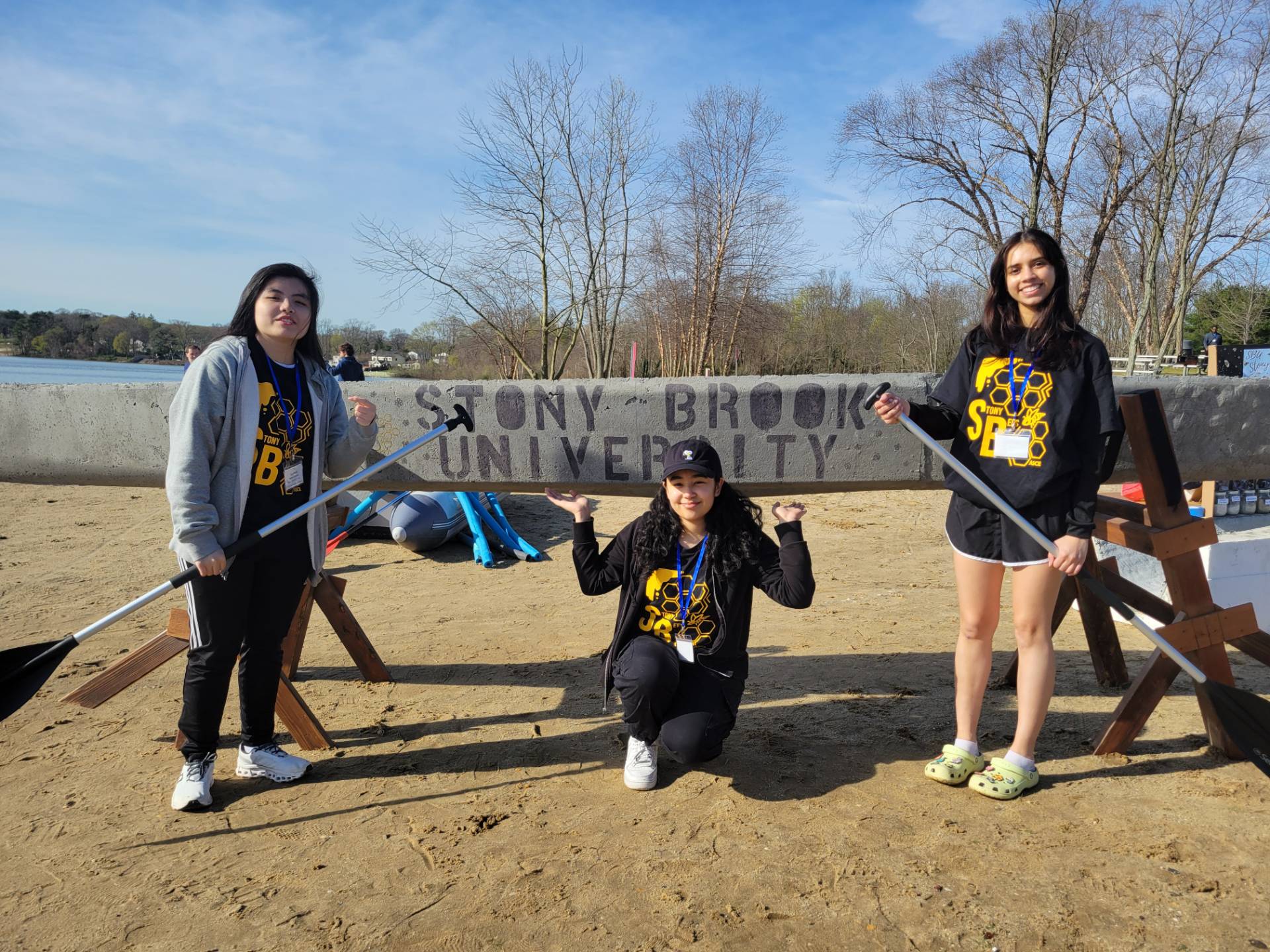 Three students standing in front of a concrete canoe with Stony Brook University painted on the front.