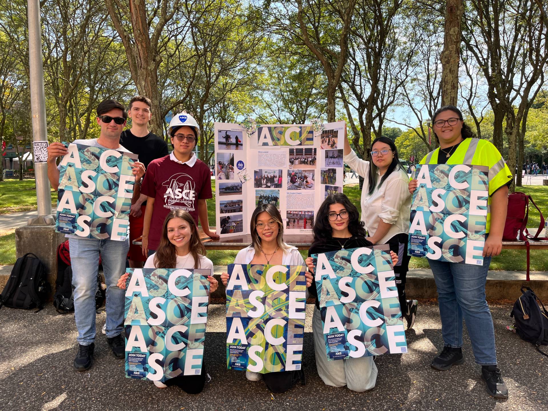 Three students standing outside with signs that say ASCE.