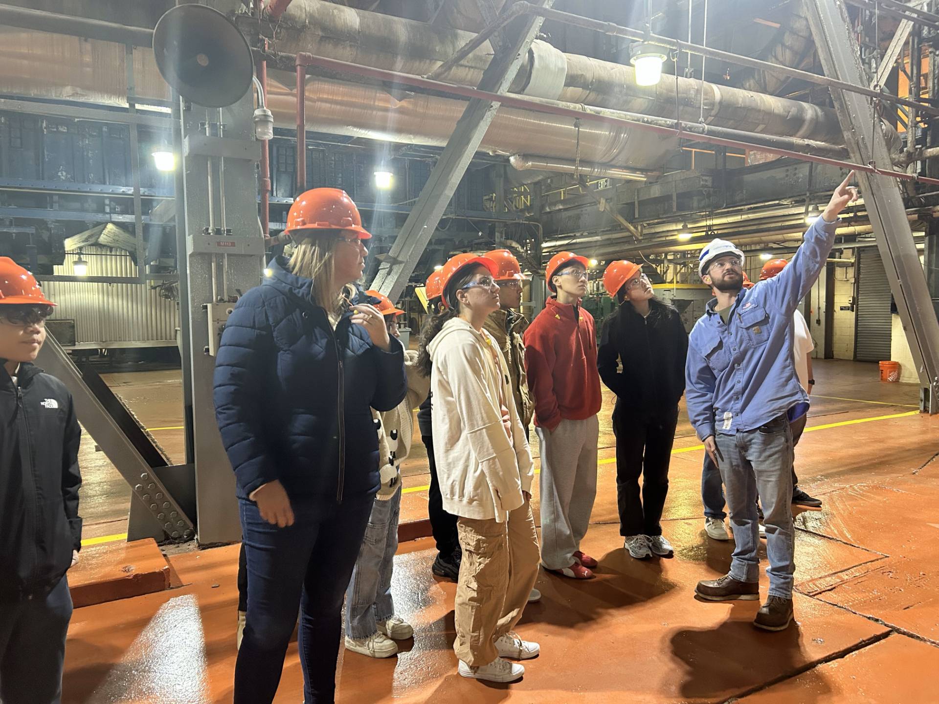 People in orange hard hats touring a facility.