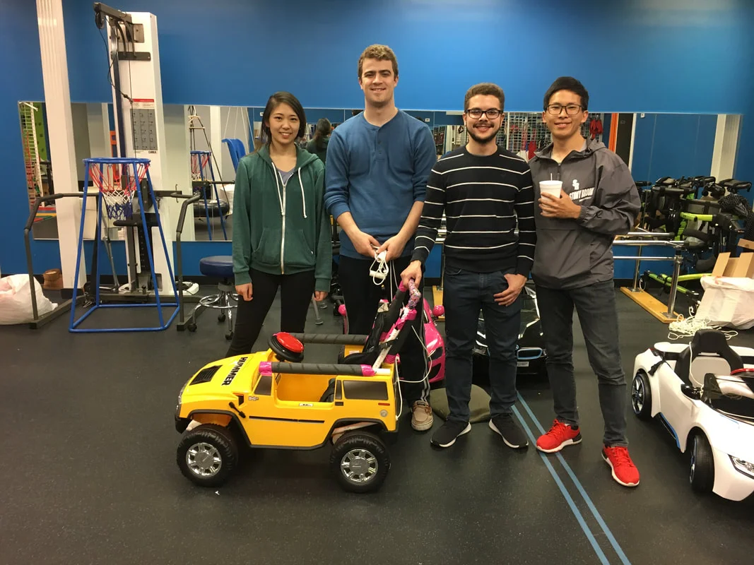 A group of individuals standing around a small, toy car.