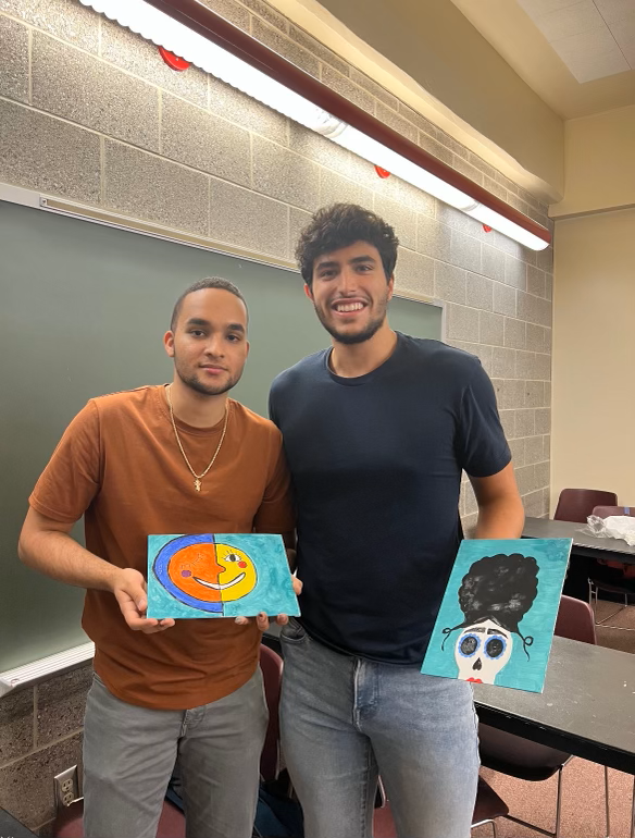 Two students holding paintings.