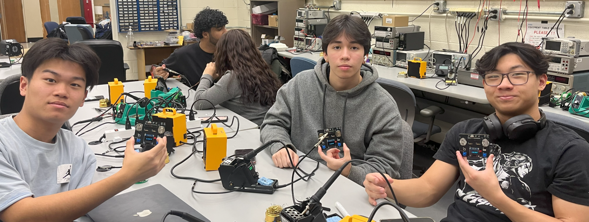 Students sitting and holding electronic circuit boards in their hands.