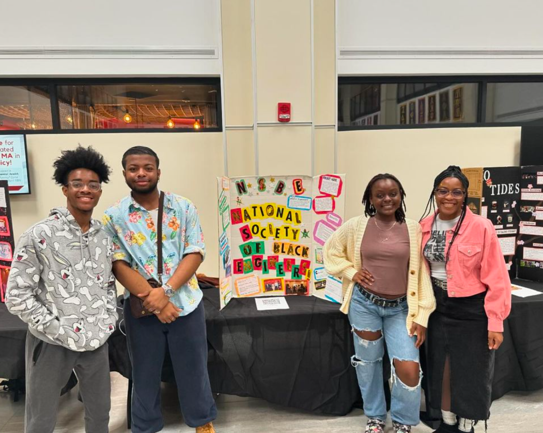 Group of students posing in front of a poster for the National Society of Black Engineers.
