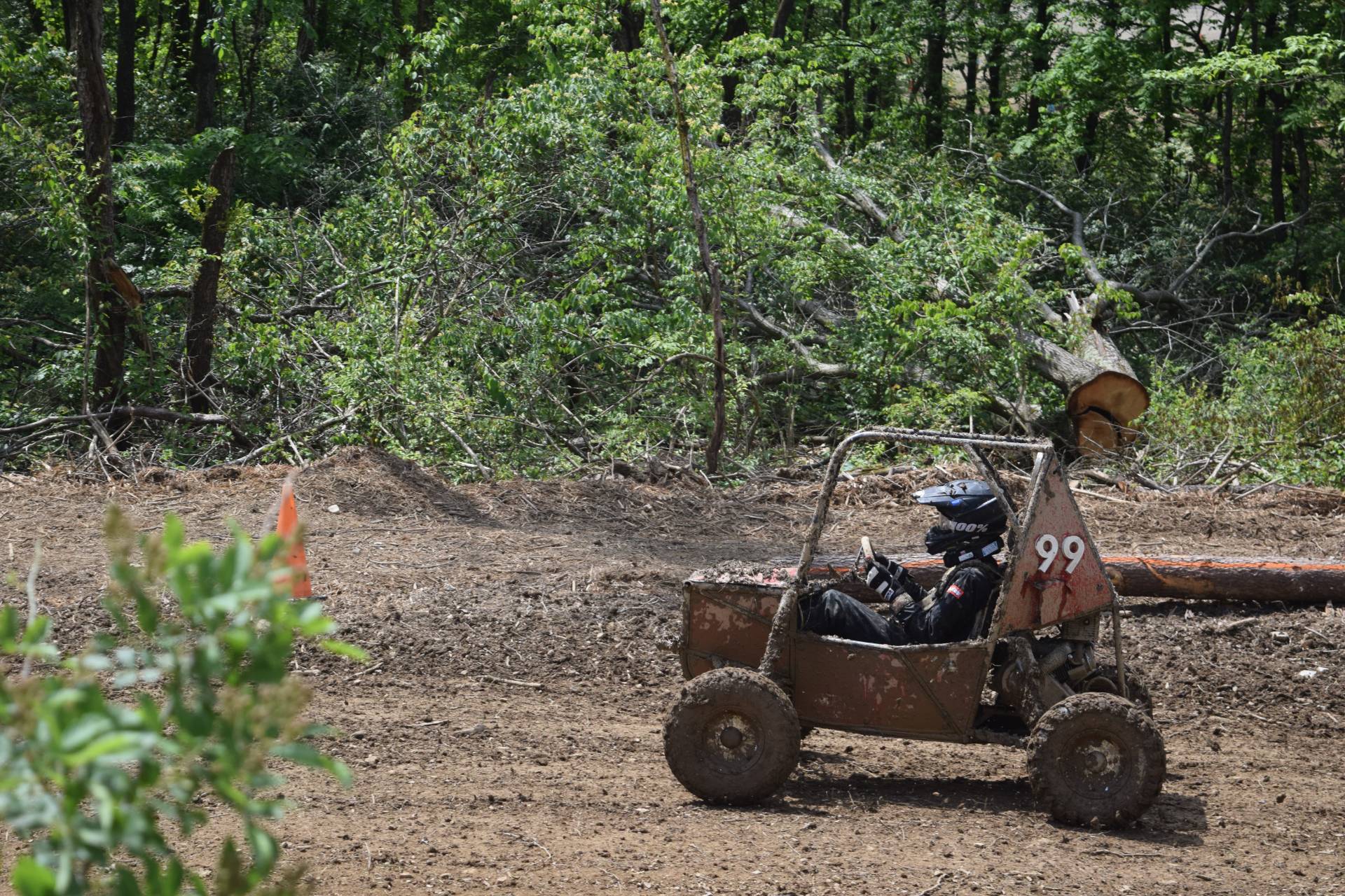 Motorsports vehicle driving on a muddy track.