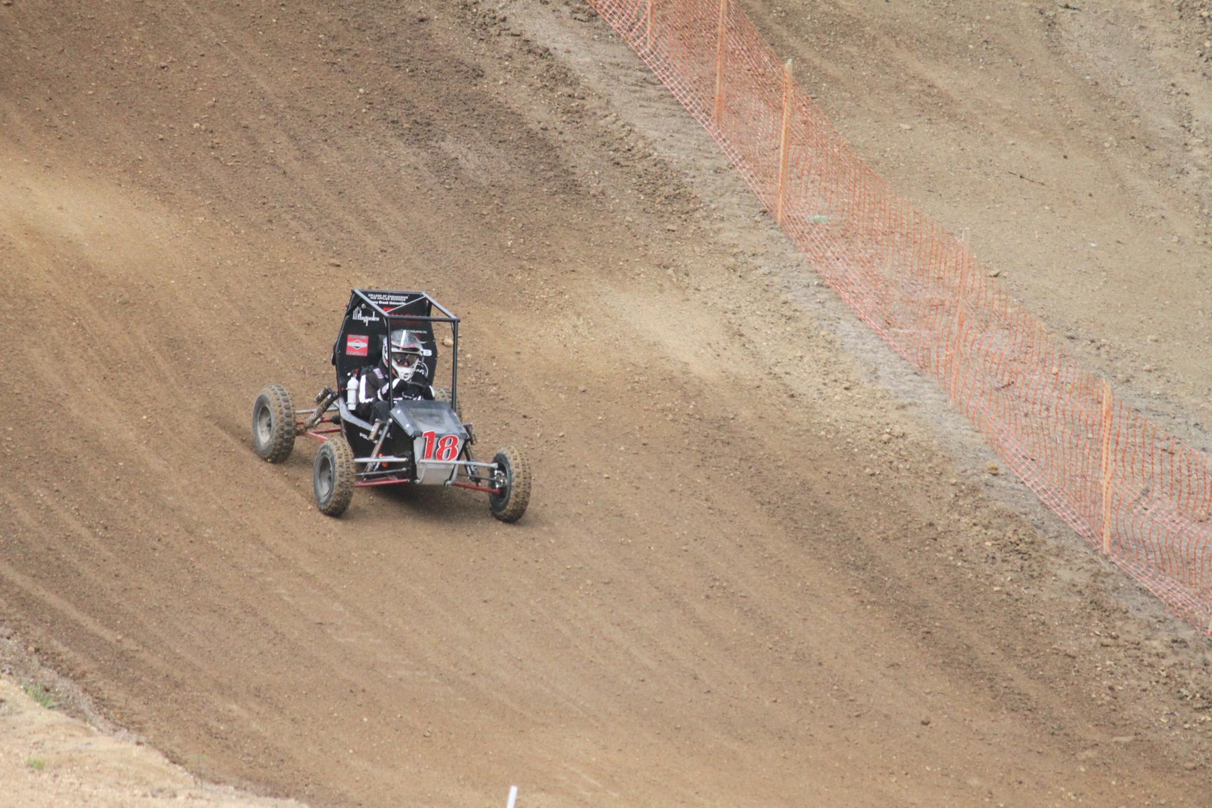 Motorsports vehicle driving down a dirt hill.