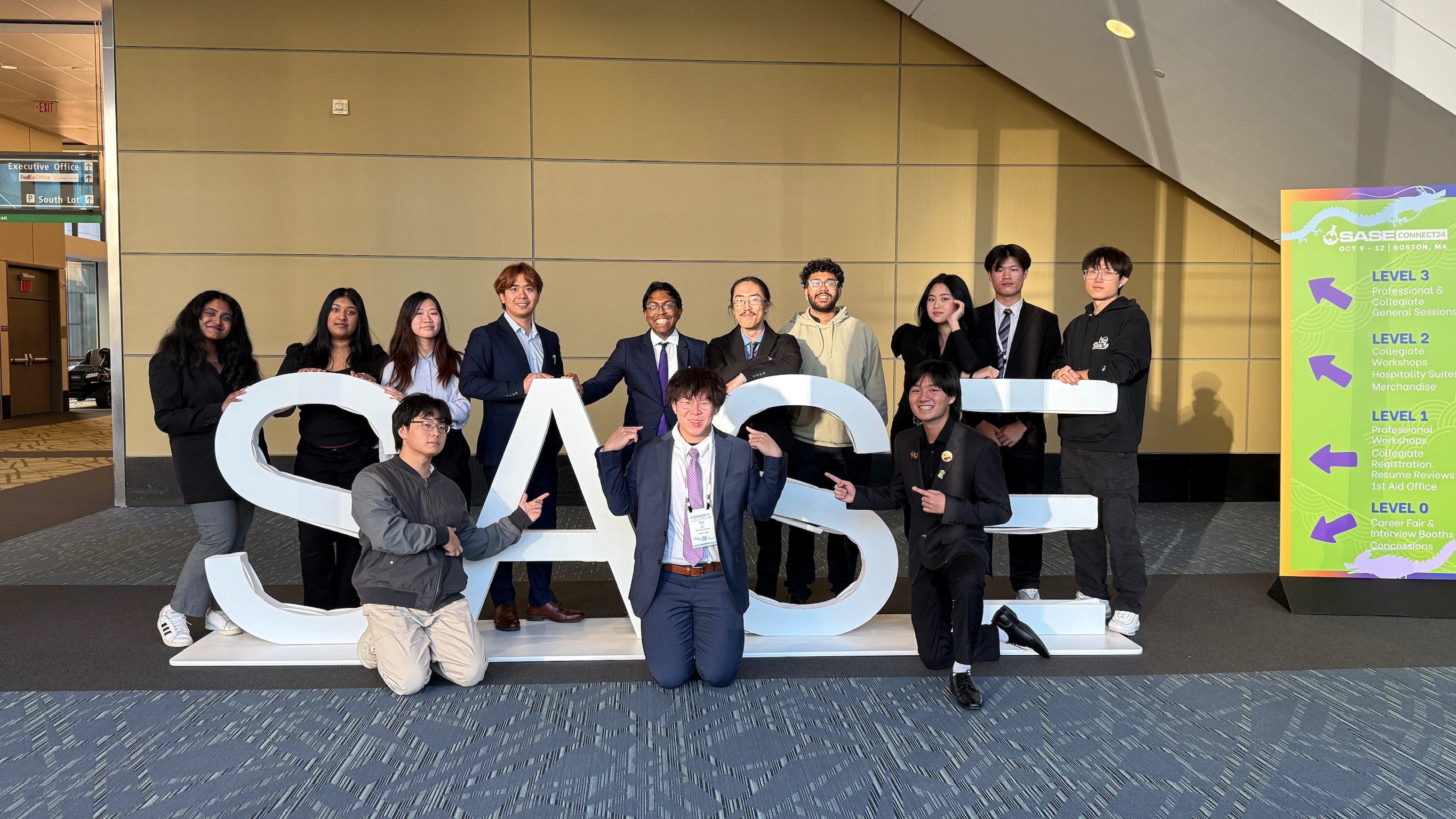 People standing in front of and behind a sign that says SASE.