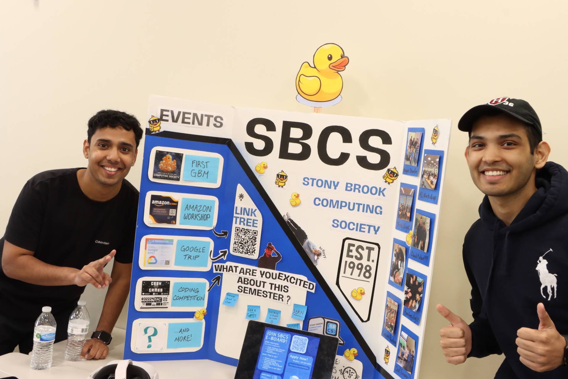 Two students standing in front of a poster that says SBCS.