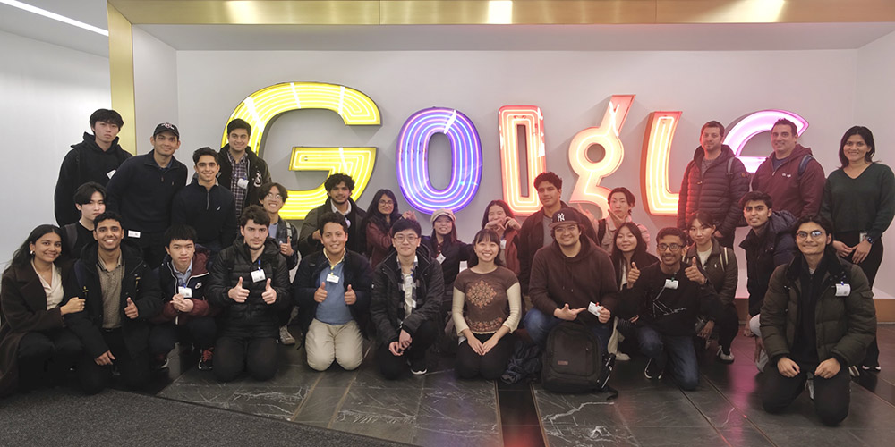 A group of people posing in front of a wall that says Google.