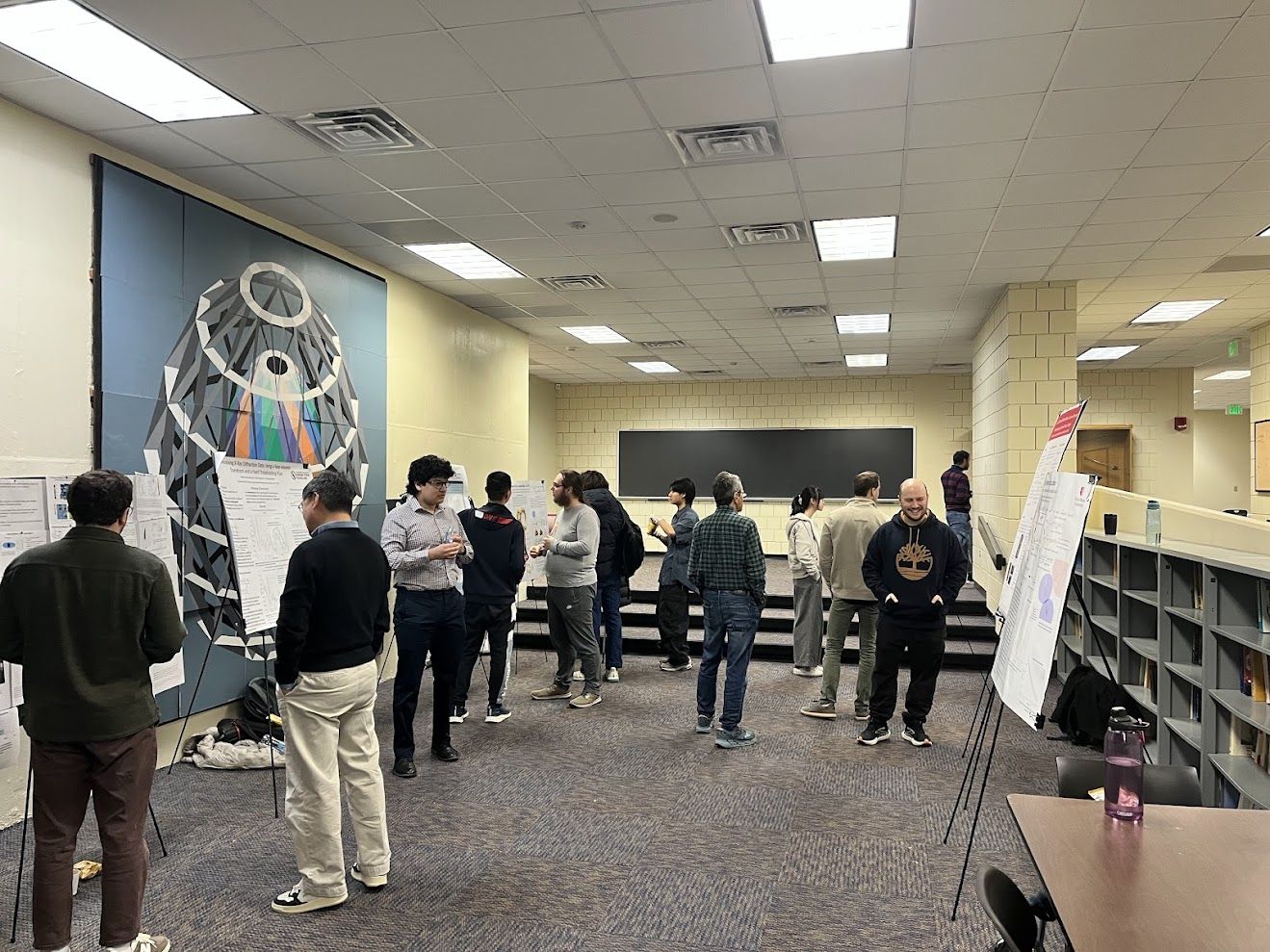 Students engaging in a large room and looking at research posters.