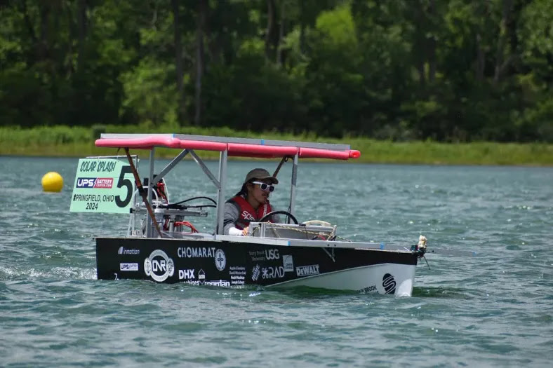 Student driving a boat on the water.