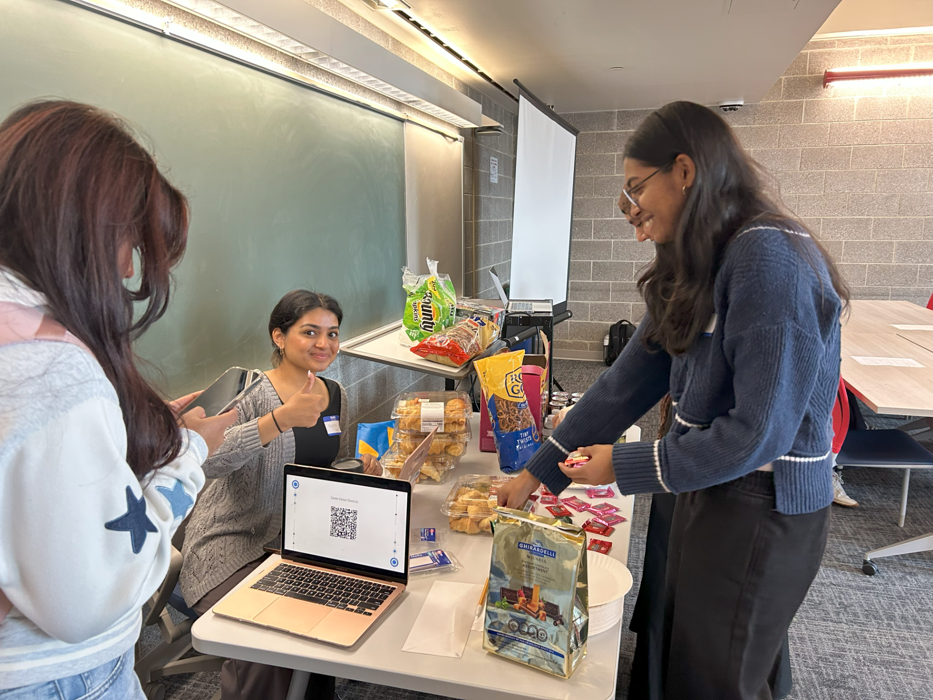 Students smiling at a desk fulled with chocolate and snacks.