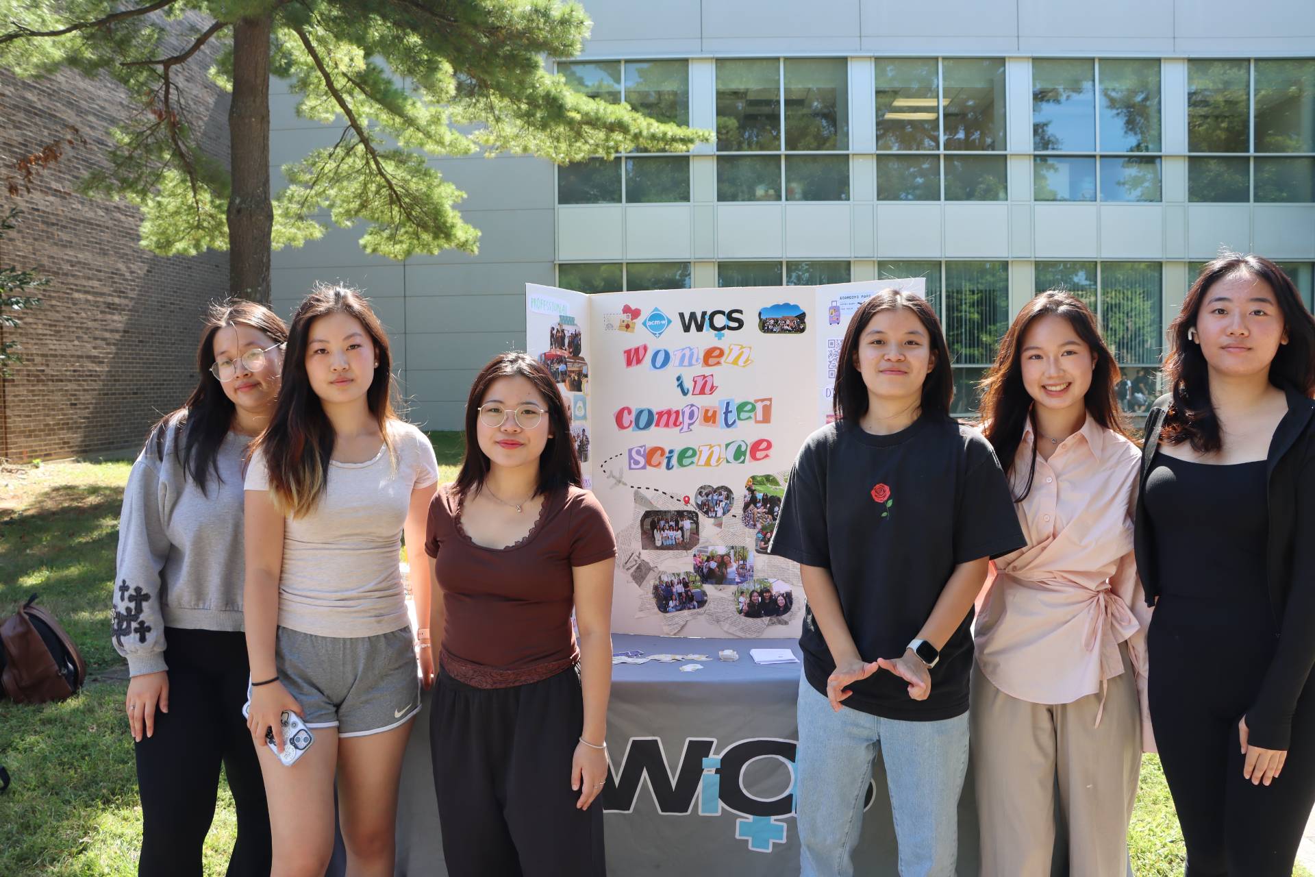A group of students standing in front of a poster board for WICS