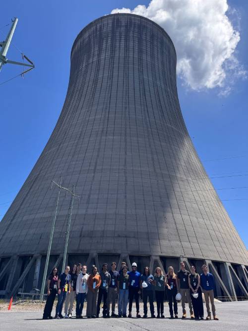Large structure in the background with a group of people posing in front for a photo.
