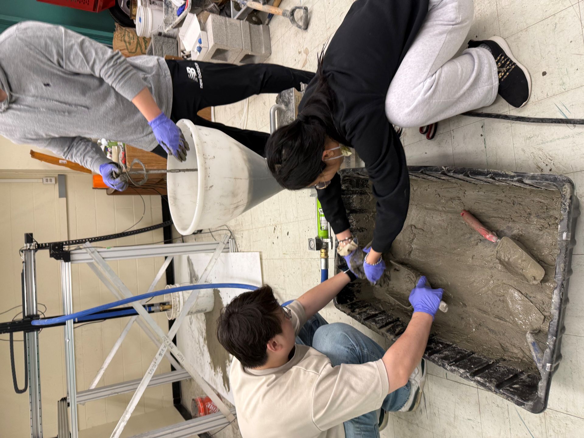 Students mixing and collecting concrete with hand trowels.