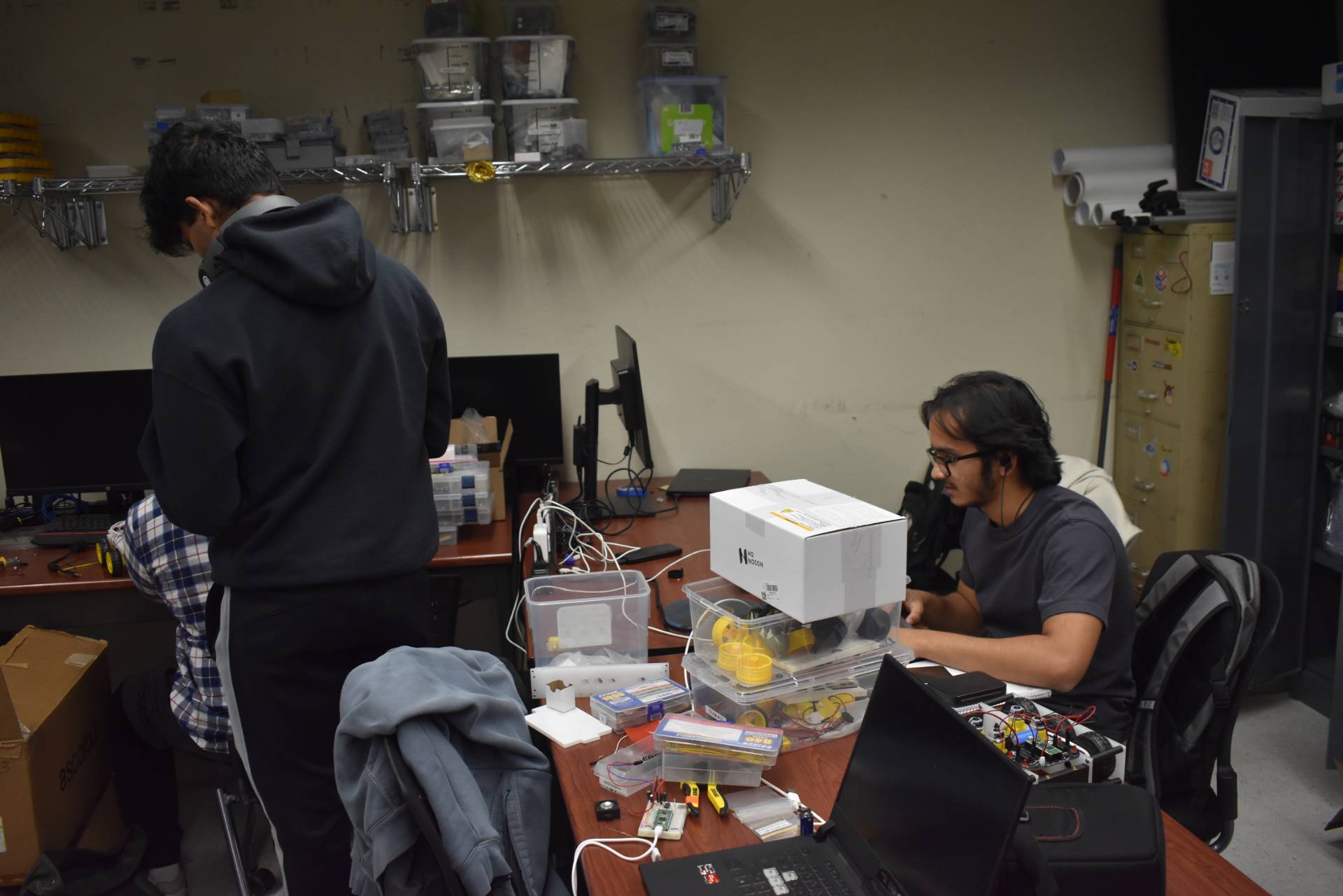 Students working in a room with circuits and items on a table