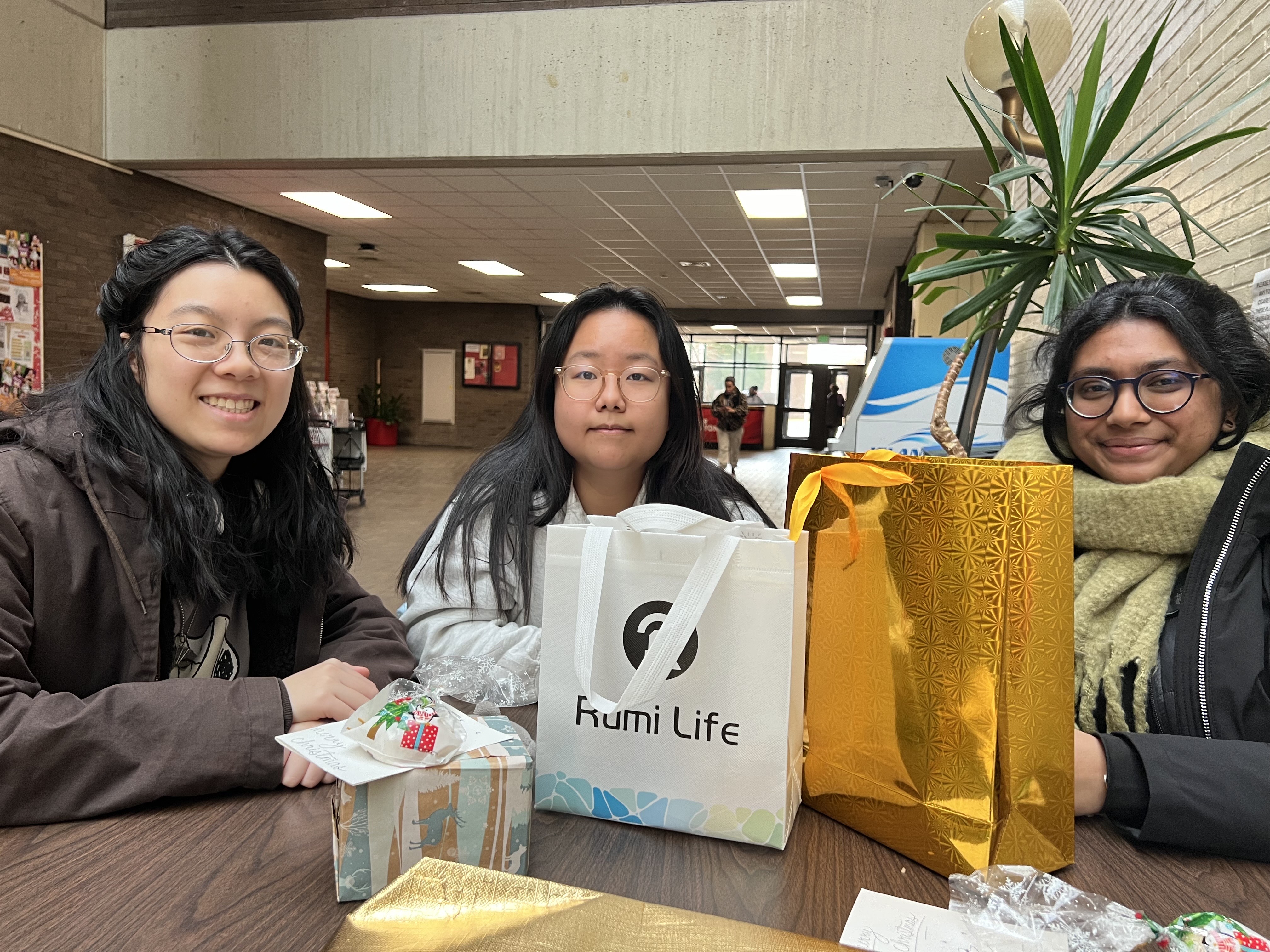 Three students sitting at a table and smiling.