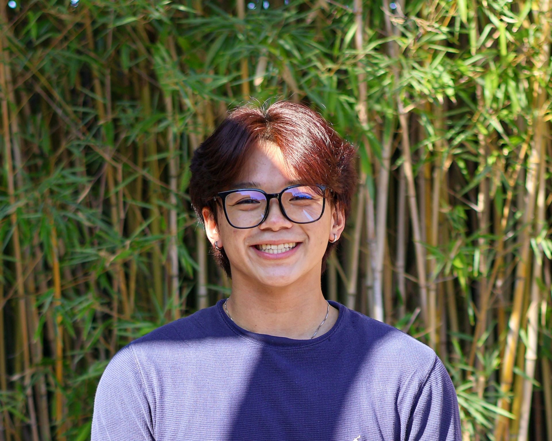 Carl Michael Go smiling while standing in front of a bamboo background.