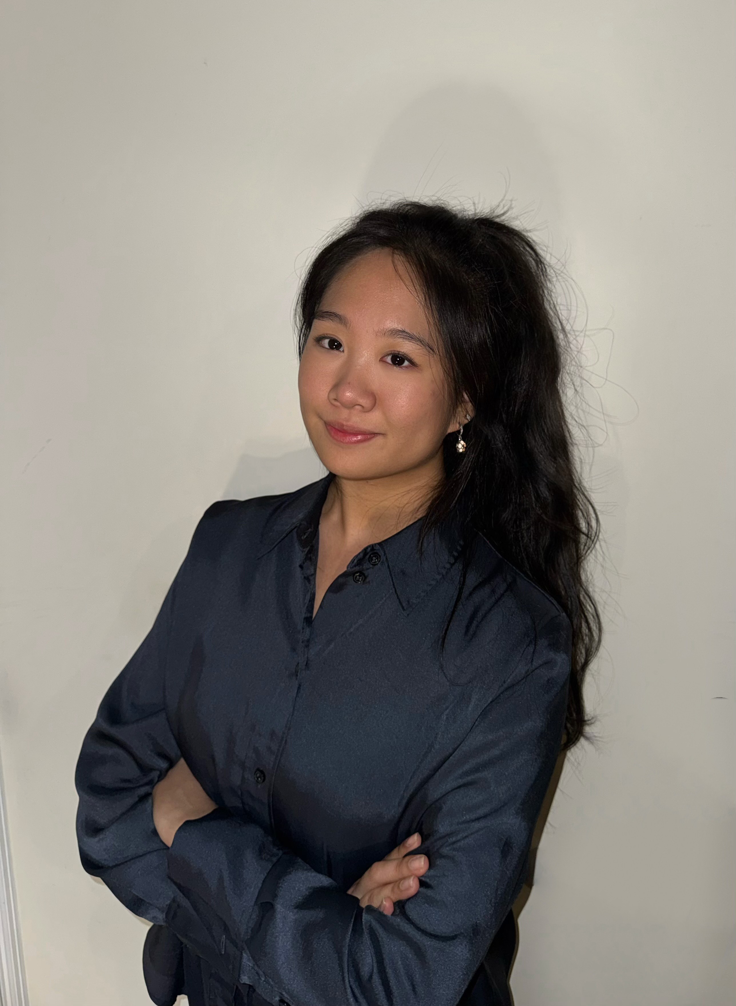 Claire Zhang posing against an off-white background with arms crossed.