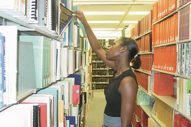 Accelerated College Education A student looking at books on a library shelf