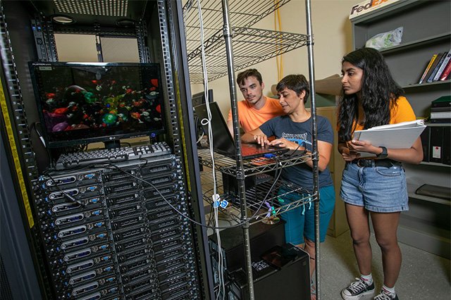 Institute for Advanced Computers Three students working on a laptop on a lab with a server