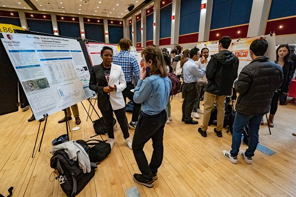 Undergraduate Research Creative Activities Students displaying their posters at an Undergraduate Research Creative Activities event in a large conference room on campus