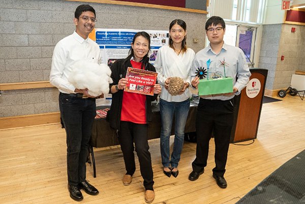Vertically Integrated Projects (VIP) Program A professor and three students are smiling in front of their table which demonstrates their project and they are holding items
