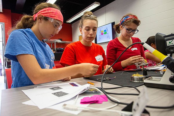 Women in Science Engineering Three female students are seated at a table and working with wires