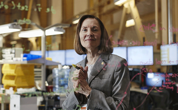 Esther Takeuchi in her lab with equations on the board.