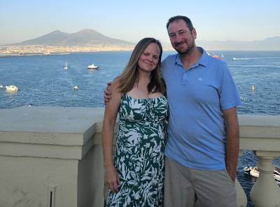 Michele Fischer and Frank Fischer in front of an ocean background with mountain behind them.