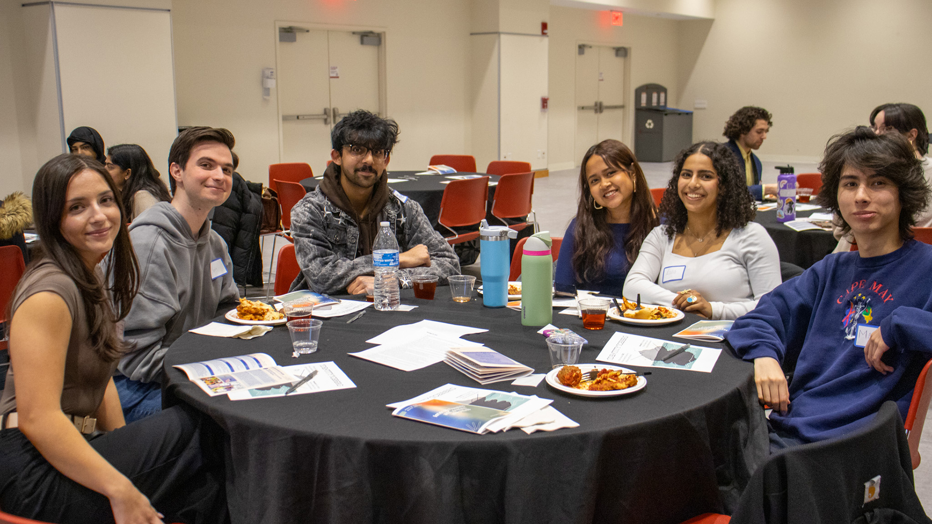 Students smiling around a table while completing a Community Dialogue discussion.