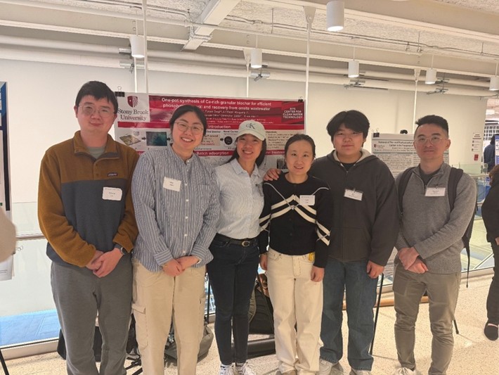Six researchers standing in front of research poster
