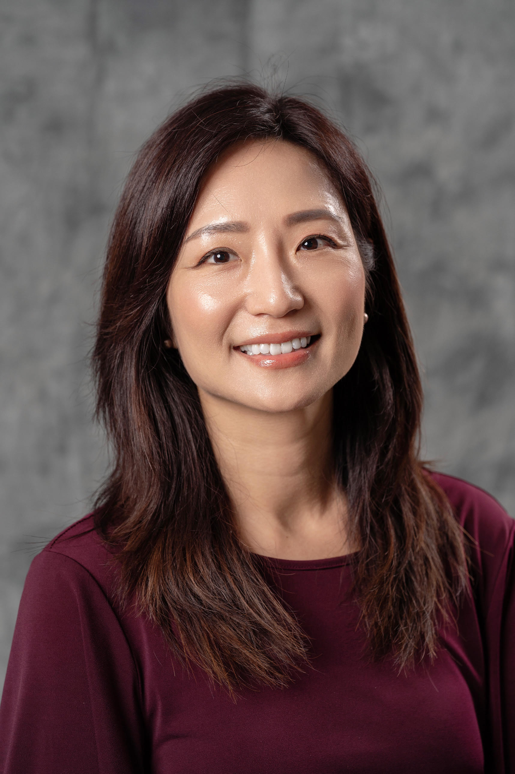 Ming Huang, with shoulder-length dark brown hair wearing a red sweater