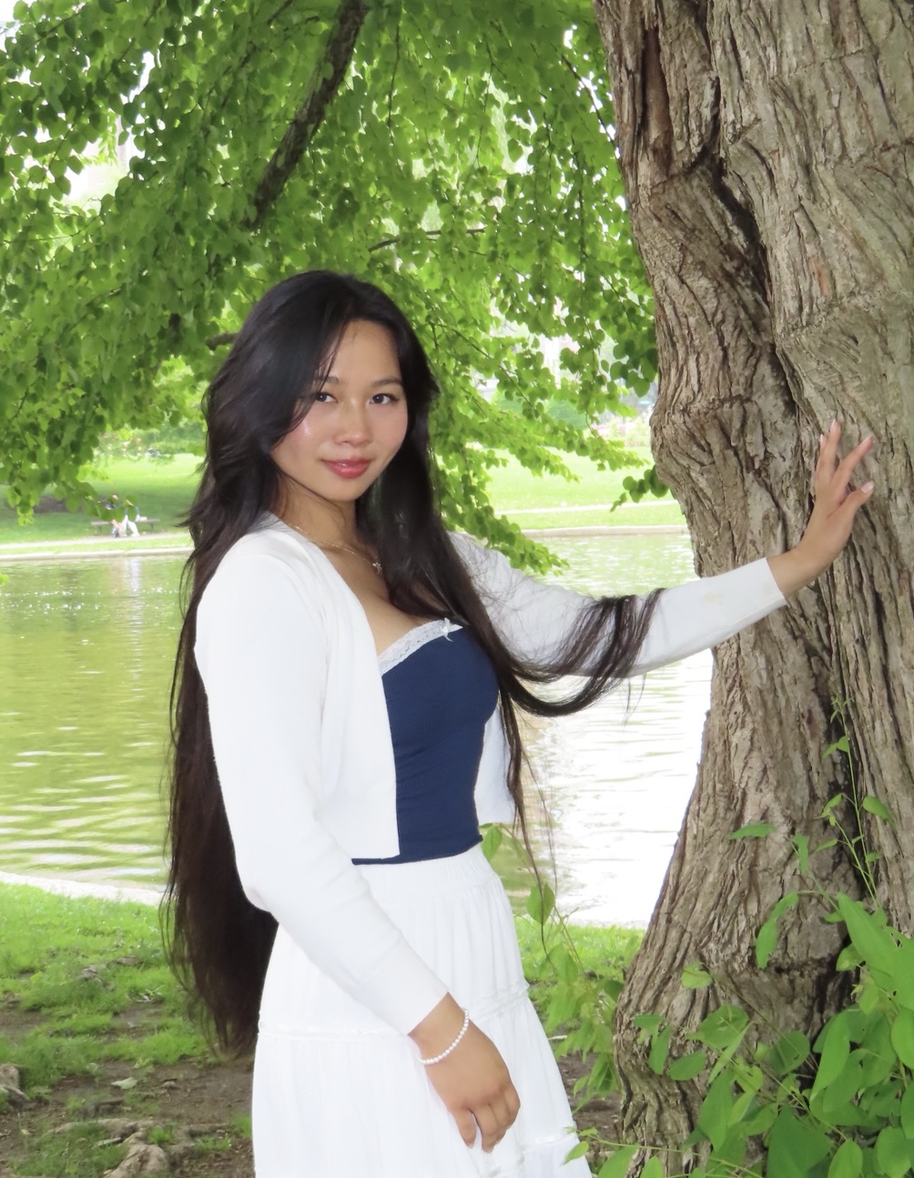 Becca Gabrielsen Person smiling and standing with their hand on a tree