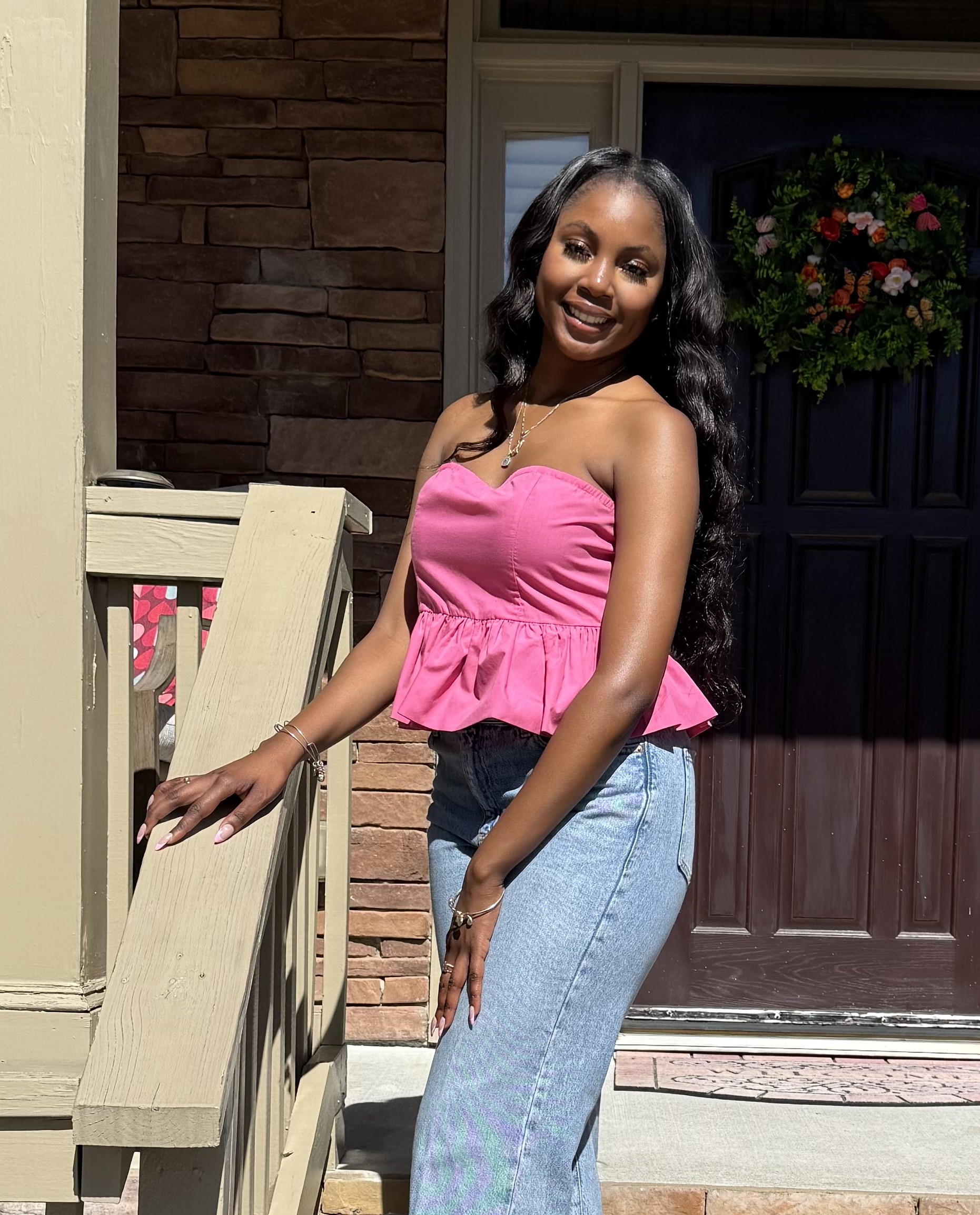 Faizah Armfield-Bility a smiling person stands on the front porch of a house