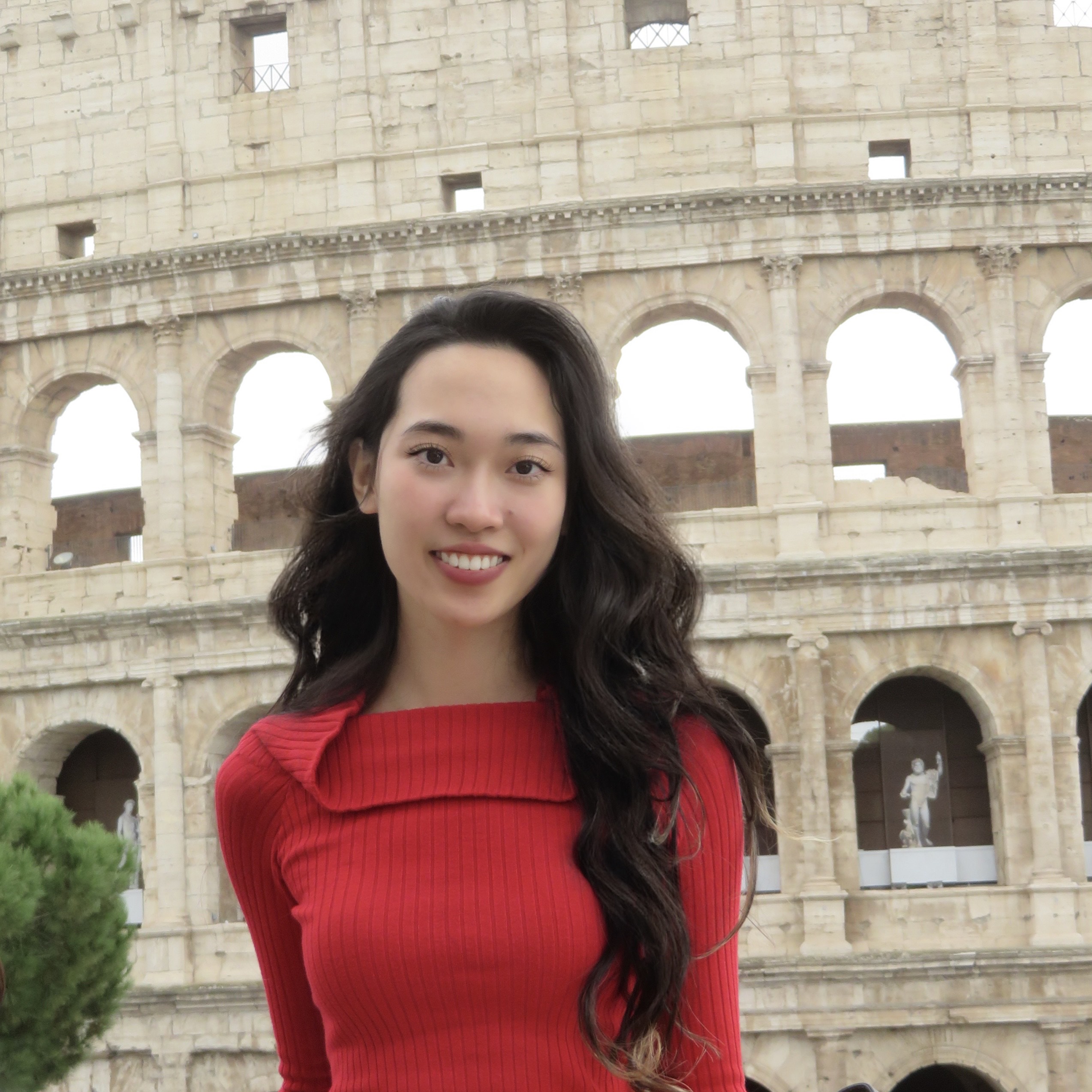Rebecca Zhang a woman wearing a red dress stands in front of a sculpture