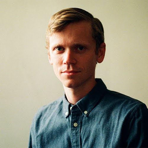 Portrait of a person in a denim shirt against a plain background.