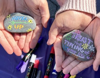 Students holding rocks of hope from our Fall 2024 event that say "Trust the Timing of Your Life" & "Never Give Up"