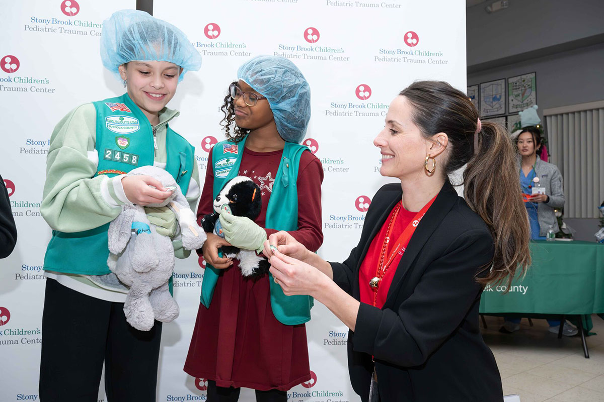 Injury prevention staff interact with two girl scouts at an event.