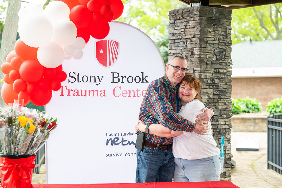 Two individuals embrace at a Trauma Survivors event.