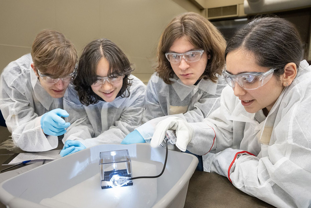 Students crowd around a table in a lab