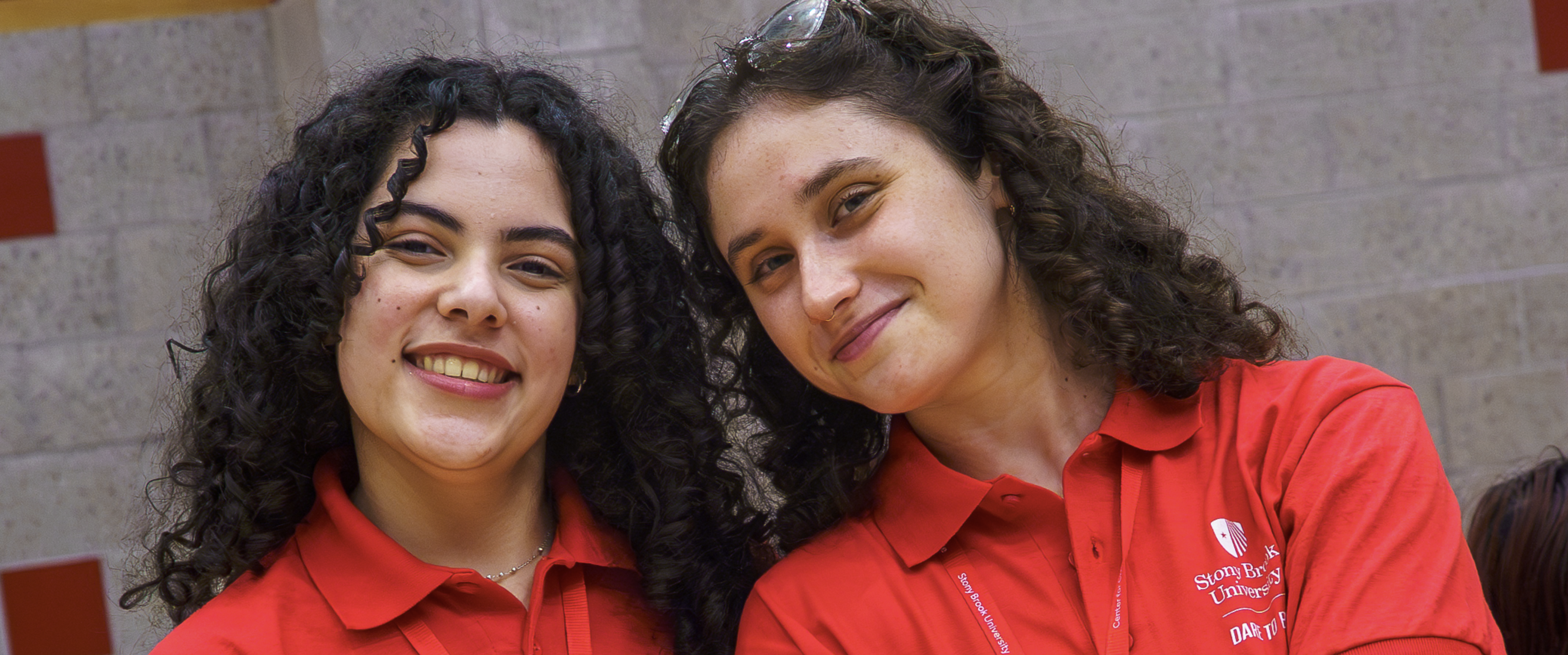 Two Students Smiling at the camera with curly brown hair