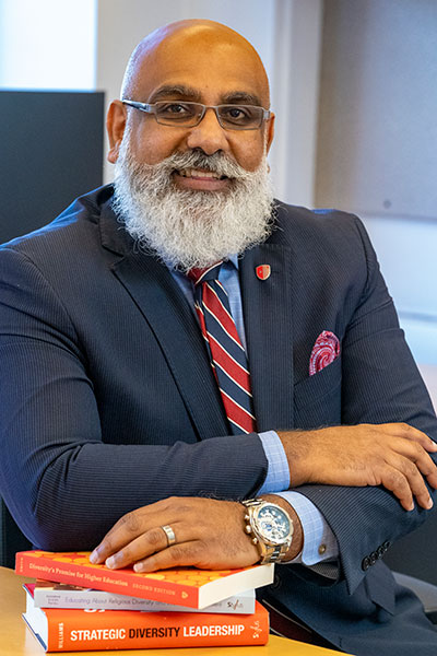 Usama Shaikh sitting at a desk with hand on books