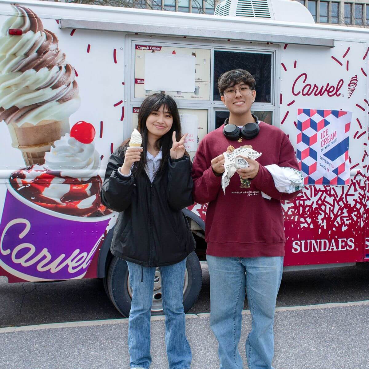 two people holding ice cream in front of the Carvel truck