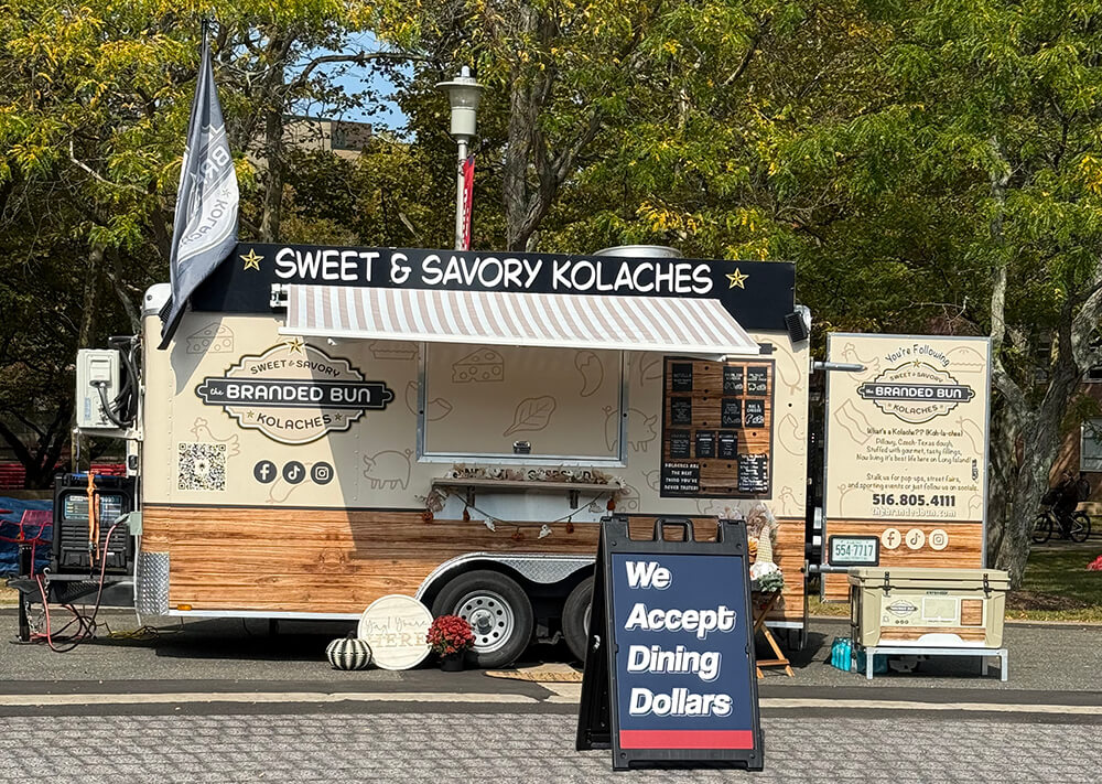 Food truck named "The Branded Bun" offering sweet and savory kolaches, with a sign saying "We Accept Dining Dollars."