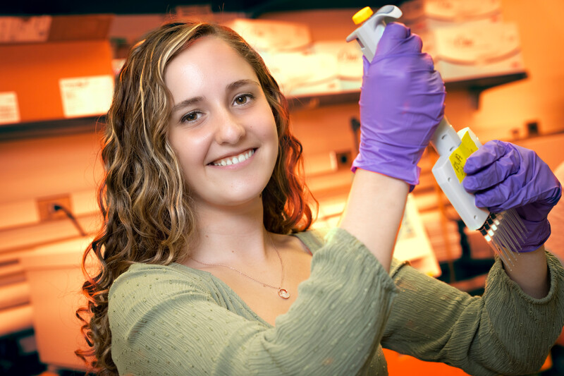 Student in the lab holding a vial