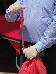 person wearing latex gloves pulling the drawstring of a red bag closed
