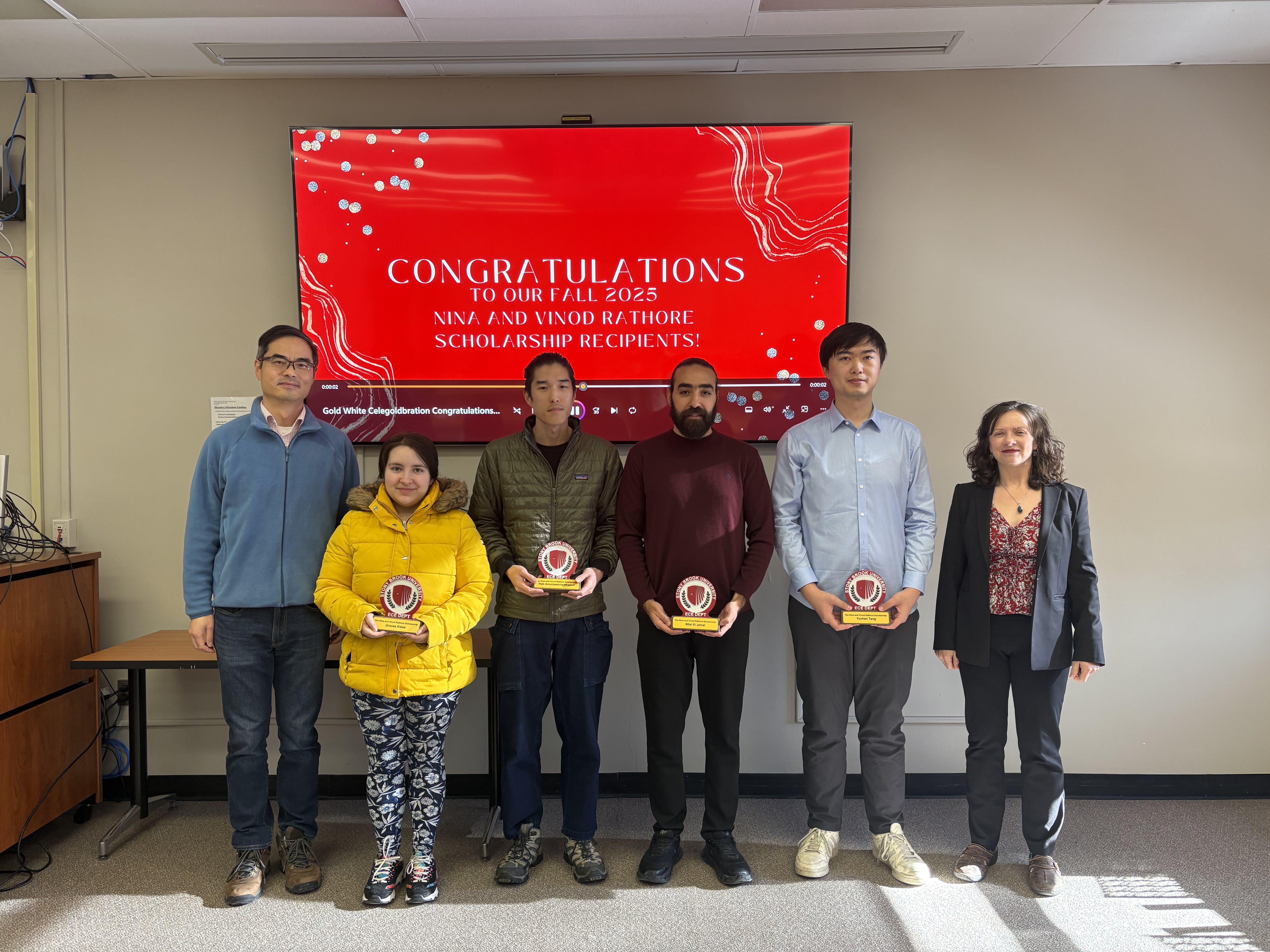 Six individuals standing in front of a screen, 4 of them holding throphies for a scholarship they were awarded.